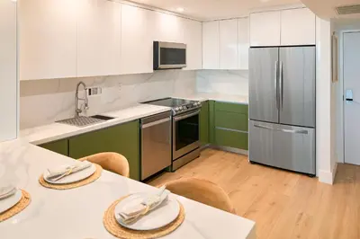 a kitchen with green cabinets and stainless steel appliances at Skyline Studio at Roney Palace - 1429 in Miami Beach