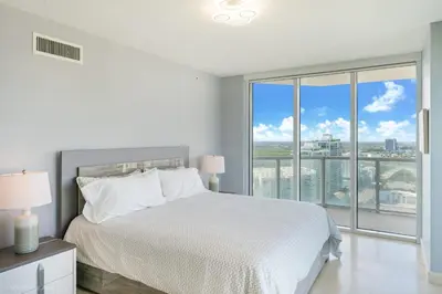 a white bedroom with a bed and a large window at A Breathtaking Oceanview - High Rise Luxury Condo in Sunny Isles Beach