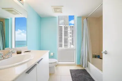a bathroom with a sink and a toilet and a window at Balcony on the Ocean - Picture Perfect in Sunny Isles Beach