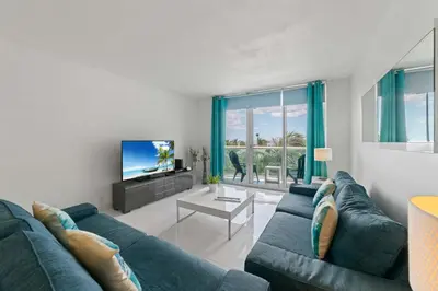 a living room with a blue couch and a tv at Ocean Wind - Luxury Beachfront Condo with Pool & Gym in Hollywood