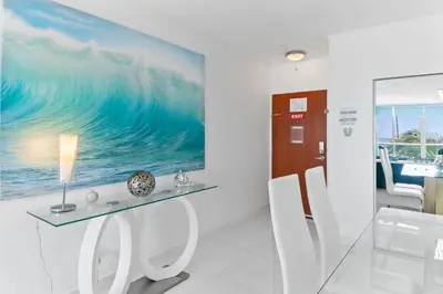 a room with a table and chairs and a large wave painting at Ocean Wind - Luxury Beachfront Condo with Pool & Gym in Hollywood