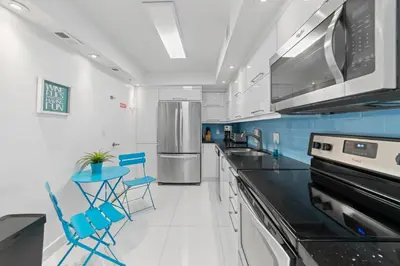 a kitchen with black counter tops and blue chairs at Ocean Wind - Luxury Beachfront Condo with Pool & Gym in Hollywood
