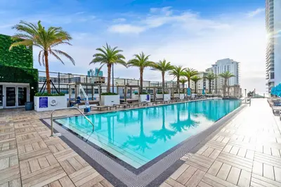 a large swimming pool with palm trees on a building at 2BR Ocean Penthouse - Private Terrace & Hot Tub in Hollywood