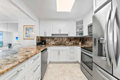 a kitchen with white cabinets and a stainless steel refrigerator at Oasis on the Beach - For 4 in Miami Beach
