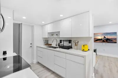 a white kitchen with white cabinets and a sink at Walk To Coral Gables | SLEEP 8| Free BEACH Package in Miami
