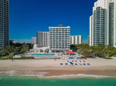 a view of a beach with some chairs and buildings at Beachfront Studio - Marco Polo Sunny Isles -2Beds in Sunny Isles Beach