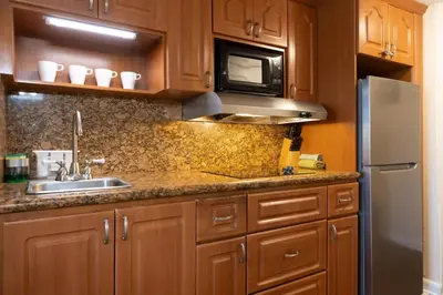 a kitchen with wooden cabinets and a sink and a refrigerator at Beachfront Studio - Marco Polo Sunny Isles -2Beds in Sunny Isles Beach