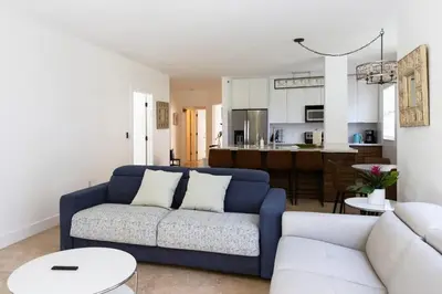 a living room with a blue couch and a kitchen at Luxe 3BR Apartment with Great Patio at Yacht Club in Aventura