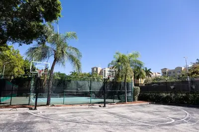 a tennis court with a basketball hoop and palm trees at Luxe 3BR Apartment with Great Patio at Yacht Club in Aventura