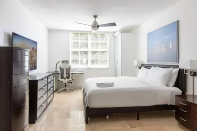 a bedroom with a bed and a desk and a window at Luxe 3BR Apartment with Great Patio at Yacht Club in Aventura