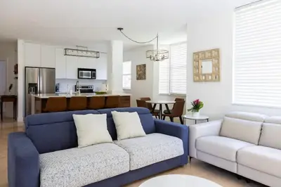 a living room with a blue couch and a kitchen at Luxe 3BR Apartment with Great Patio at Yacht Club in Aventura