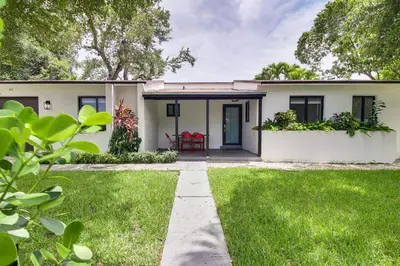 a white house with a red chair in the yard at 5 Mi to Beach Group Getaway with Yard in Miami in Miami