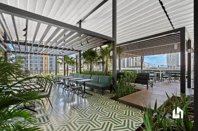a rooftop patio with tables and chairs in a building at Stylish Sky-High Condo with Pool and Gym in Miami