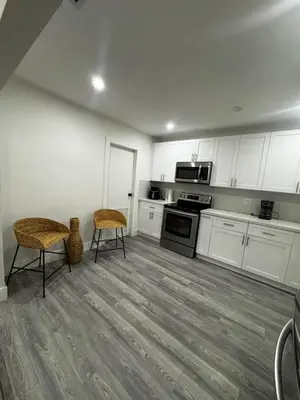 a kitchen with white cabinets and two chairs at Santuaria Hollywood in Hollywood