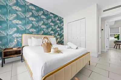 a bedroom with a large bed with a tropical wallpaper at Byron Avenue Suites in Miami Beach