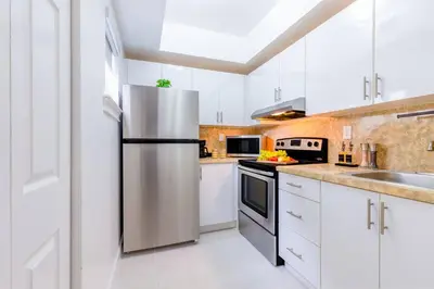a kitchen with white cabinets and a stainless steel refrigerator at Prime Miami Retreat | Sleeps 12 | Parking, BBQ! in Miami