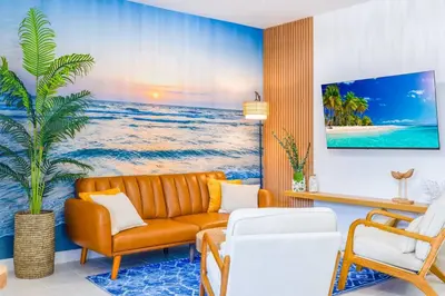a living room with a couch and a palm tree at Beachy Living |Sleep 8 Best Location | BBQ & Patio in Miami