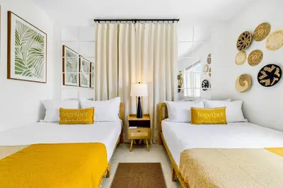 two beds in a room with white walls and yellow pillows at Tropical | 8PPL | Top Location | Parking | Laundry in Miami