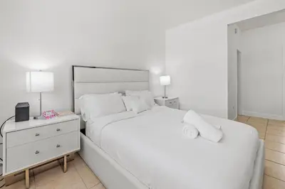 a white bedroom with a large bed and a nightstand at Stay in Brickell near Kaseya Center & South Beach in Miami
