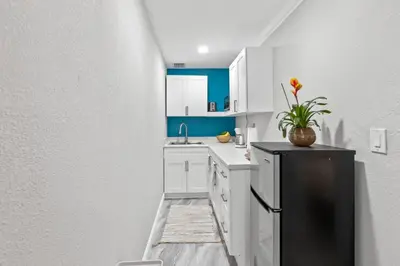 a kitchen with white cabinets and a black refrigerator at Charming Hideaway Near Beach, Nightlife & Shops in Fort Lauderdale
