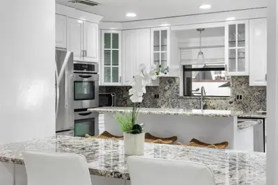 a kitchen with white cabinets and a marble counter top at Cherry RoyaleGrand Villa in Davie