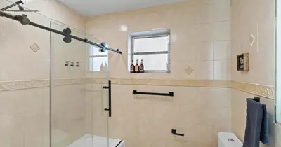 a bathroom with a shower and a toilet and a window at Chicago Vibe Heated Pool 5BR 2BTH in Miami
