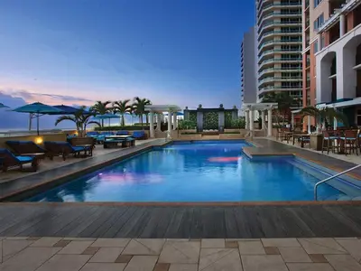 a swimming pool with tables and chairs and a building at Marriott's BeachPlace Towers 1BR Apartment with Resort Access in Fort Lauderdale