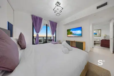 a bedroom with a large white bed with purple curtains at Chic 2-Bedroom Downtown Condo with Breathtaking City & Waterfront Views in Miami