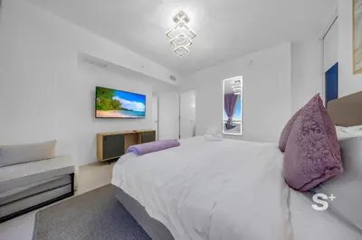 a white bedroom with a large bed and a tv at Sleek 3-BD Downtown Miami Condo with Water & City Views in Miami