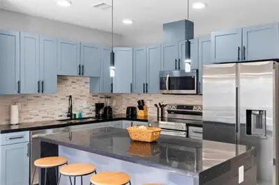 a kitchen with white cabinets and a counter with stools at Urban Comfort - 20min to Beach & Airport in Miami