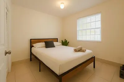 a bedroom with a large white bed with a window at Casa Rosa Wynwood in Miami