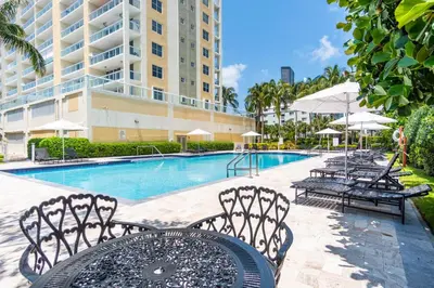 a pool with chairs and a table and a building at Golden Bay 504 in Sunny Isles Beach