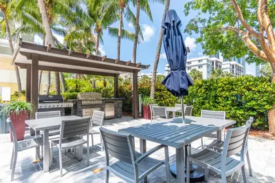 a table and chairs with an umbrella and a grill at Golden Bay 504 in Sunny Isles Beach