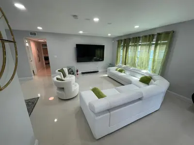 a white living room with two white couches and a tv at Spacious 4BR Home 5 Min from Hard Rock Stadium in Miami Gardens