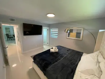 a bedroom with a large bed and a flat screen tv at Spacious 4BR Home 5 Min from Hard Rock Stadium in Miami Gardens