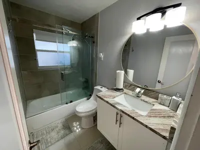 a bathroom with a toilet and a sink and a mirror at Spacious 4BR Home 5 Min from Hard Rock Stadium in Miami Gardens