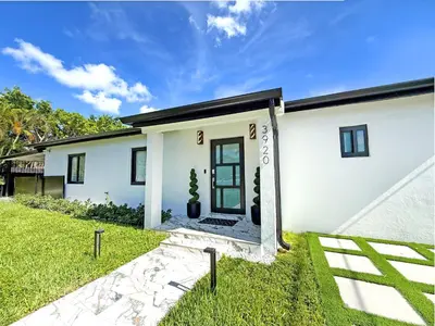 a white house with a front door and grass at The LuxeLanding MIA- Swimming pool, Oasis Lounge, Mini Golf, BBQ and Hibachi Grill , and Outdoor Games in Miami
