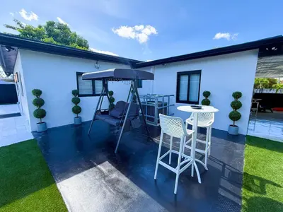 a patio with a table and chairs and an umbrella at The LuxeLanding MIA- Swimming pool, Oasis Lounge, Mini Golf, BBQ and Hibachi Grill , and Outdoor Games in Miami