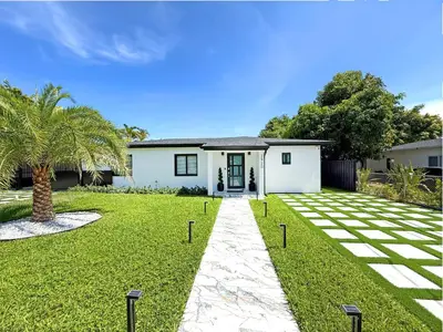 a white house with a palm tree in the yard at The LuxeLanding MIA- Swimming pool, Oasis Lounge, Mini Golf, BBQ and Hibachi Grill , and Outdoor Games in Miami