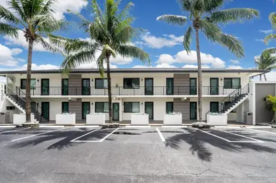 a building with palm trees in a parking lot at Comfort and Space Fort Lauderdale Miami in Fort Lauderdale