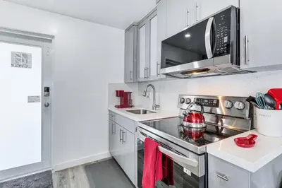 a kitchen with white cabinets and a stove top oven at 8 Mi to Design District Miami Home with Yard in Miami