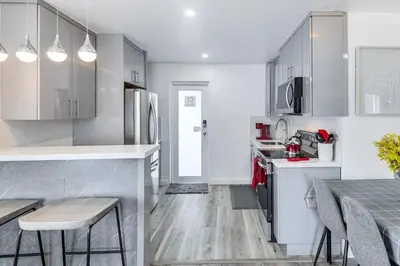a kitchen with white cabinets and a table with stools at 8 Mi to Design District Miami Home with Yard in Miami