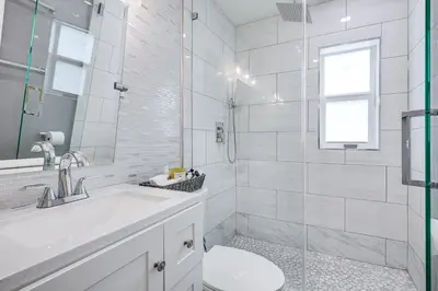 a white bathroom with a toilet and a shower at 8 Mi to Design District Miami Home with Yard in Miami