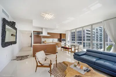 a living room with a blue couch and a kitchen at Sublime Ocean & Pool View Unit At Icon Brickell in Miami