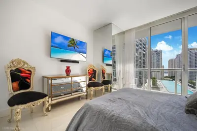 a bedroom with a bed and two chairs and a large window at Sublime Ocean & Pool View Unit At Icon Brickell in Miami