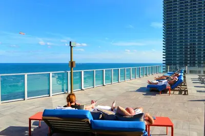 a group of people laying on lounge chairs on the beach at Charming Condo for Your Dream Vacation in Hollywood