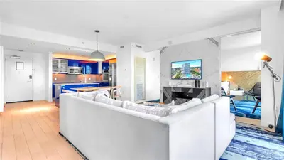 a living room with a white couch and a kitchen at Exclusive Beachfront Condo at W Fort Lauderdale in Fort Lauderdale