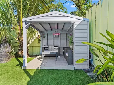 a white pergola with a table and chairs in a yard at The Velvet Palm Midtown Pool and Hot Tub in Miami