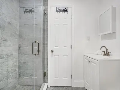 a bathroom with a shower and a white door at Bungalow House 6 BR Pool Little Havana in Miami