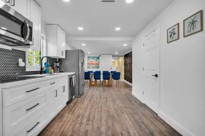 a kitchen with white cabinets and blue chairs at La Pergola Villa 7 BR PoolHot Tub Location in Miami